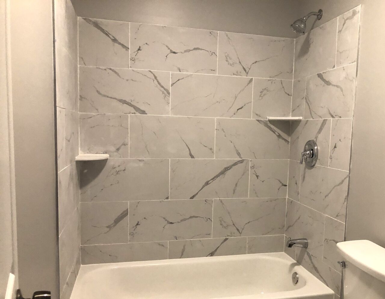 Marble-look tiled tub and shower surround with chrome fixtures