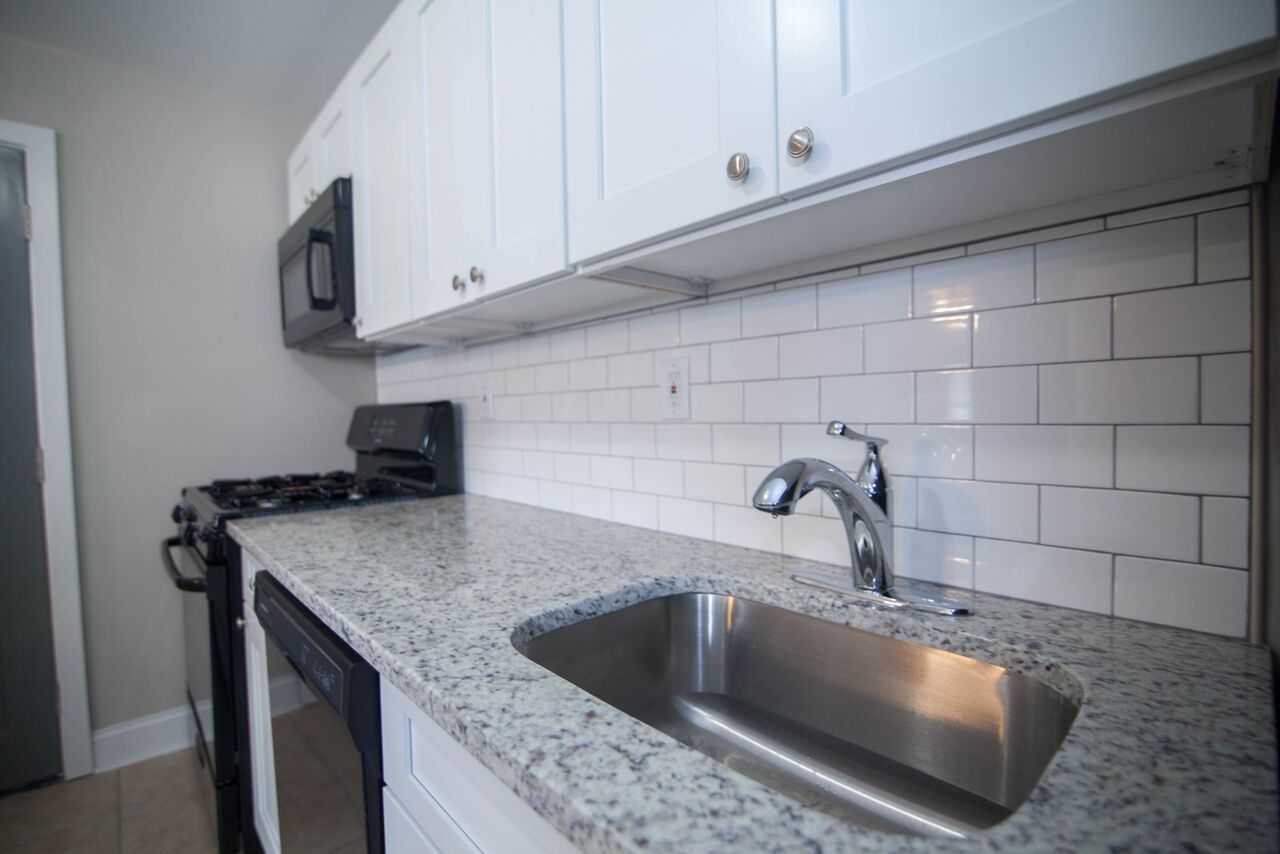 Close-up of granite counter with stainless undermount sink and subway tile